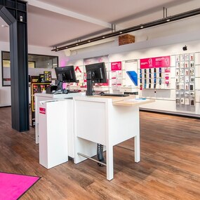 Moderner Telekom-Shop mit Smartphones, Zubehör und Beratungstresen auf hellem Holzboden.